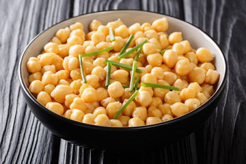 Cooked chickpeas close-up in a black bowl on a table. horizontal background