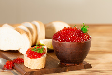 red caviar in a ceramic dish on a wooden background in a rustic style with space for text