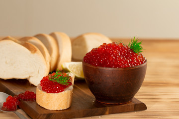 red caviar in a ceramic dish on a wooden background in a rustic style with space for text