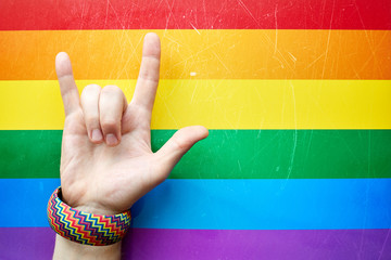 "I love you" in American sign language (ASL) which shows a man's hand on the background of the flag of LGBTQ (LGBT) community