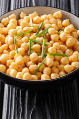 Fresh boiled organic chickpeas with green onions close-up in a bowl. vertical