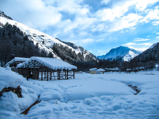 Beautiful winter landscape with small buildings, small thermal spring, valley and mountain range