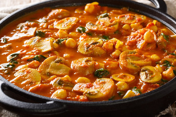 Hot Asian mushroom curry with spinach and chickpeas close-up in a pan. horizontal