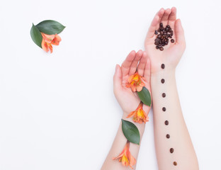 Female hands with coffee grains and hibiscus flowers and petals on a white background, fashionable art, copy space, organic