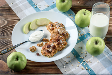 Homemade oat pancakes with vegan yogurt, raisins and walnut on the wooden table with blue fabric in the box. 