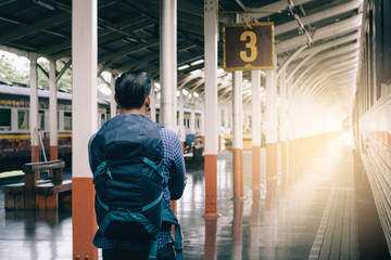 Hipster man standing at platform train station waiting and looking future concept.