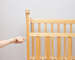 The girl collects a cot for a child, close-up, copy space, assembling