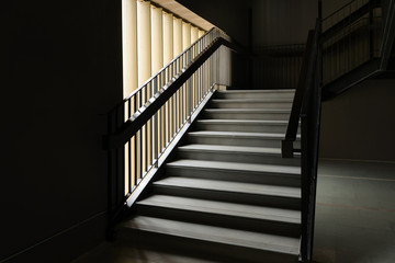 Empty Modern Concrete Staircase and black steel handrail with natural light, staircase in modern building - Dark Tone
