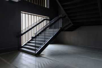 Empty Modern Concrete Staircase and black steel handrail with natural light, staircase in modern building - Dark Tone