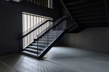 Fotobehang Trappen Empty Modern Concrete Staircase and black steel handrail with natural light, staircase in modern building - Dark Tone
