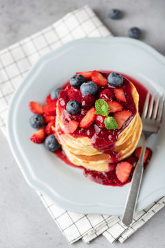 Pancakes with berries and berry sauce on plate. Closeup view, selective focus