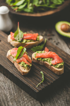 Healthy Open Sandwiches With Avocado and Salmon On Wooden Cutting Board. Selective focus, Toned image