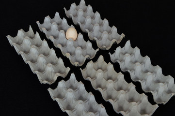 Six egg boxes with one hen egg on a black mat background