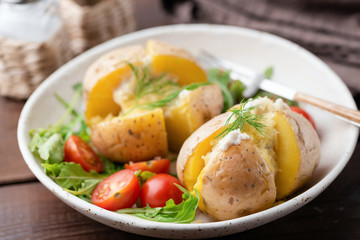 Baked stuffed potatoes with cheese, sour cream and dill on a plate. Healthy tasty dinner