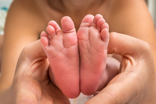 Newborn baby feet in hands of mother