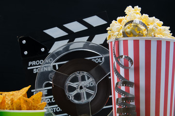 on a black background, a bucket of popcorn, a bucket of nachos, film and double for filming