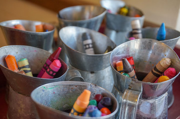Obraz na płótnie Canvas Colorful set of used crayons in tiny pitcher tins, used at a restaurant for a kid's activity to stay occupied and have fun while eating at a restaurant.