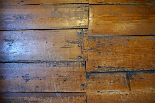 Old wood floors set in an uneven pattern, with nails showing. Some window light. Scratched and scuffed.