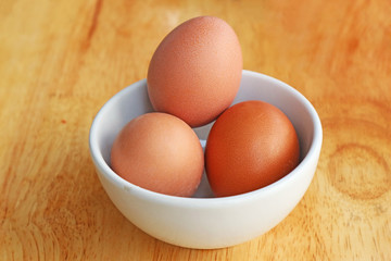 Fresh Eggs in the White Bowl on the Wooden Table