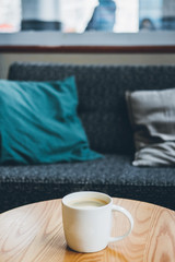Coffee cup on sofa pillow with cafe interior background