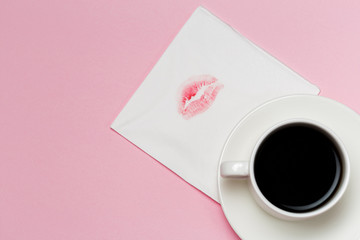 Napkin with a kiss and coffee cup on pink background.