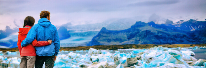 Iceland glacier landscape tourists couple at Jokulsarlon lake. Winter adventure hiking people. Panorama banner background.