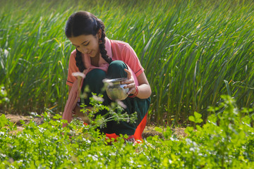 Happy little girl watering soil sitting in agriculture field.	