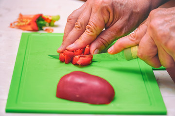 Cuts with knife into pieces red bell pepper