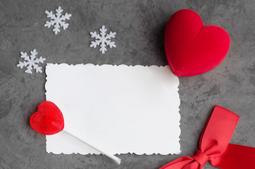 Red heart, red heart shape candle,red bow and snowflakes  on winter background with white paper...