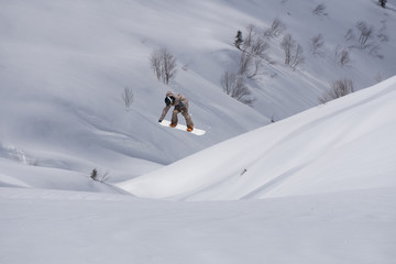 Naklejka na ściany i meble Snowboarder flying on the background of snowy slope. Extreme winter sports, snowboarding. Copy space.