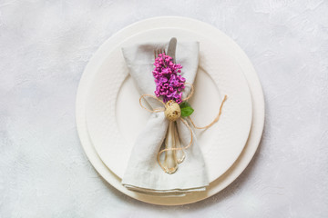 Fototapeta na wymiar Easter romantic dinner. Elegance table setting with lilac flowers on light table. Top view.