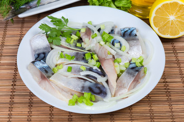Sliced salted Atlantic mackerel with onion on dish close-up