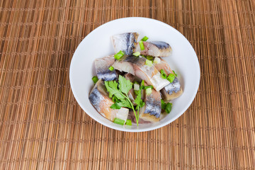 Sliced smoked Atlantic mackerel in bowl on bamboo table mat