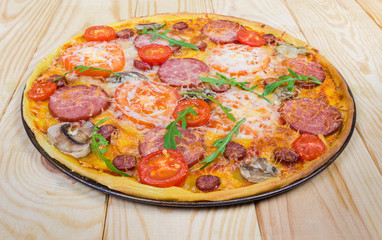 Cooked round pizza with sausages and mushrooms on baking tray