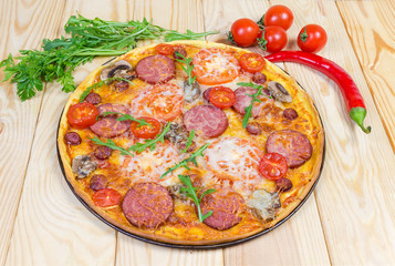 Cooked round pizza with sausages and mushrooms, greens and vegetables