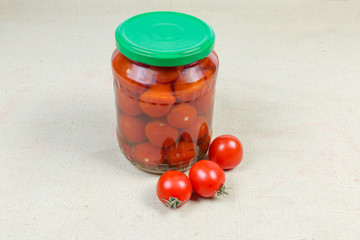 Canned and fresh cherry tomatoes on a fabric surface
