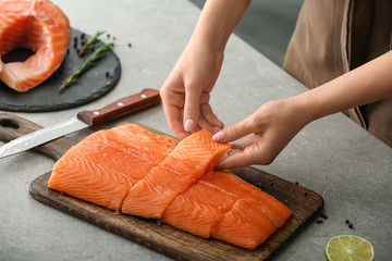 Woman with cut fillet of fresh salmon at table