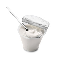 Plastic cup of tasty yogurt and spoon on white background