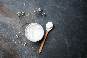 Bowl and spoon with tasty yogurt on dark background