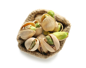 Bag with tasty pistachio nuts on white background