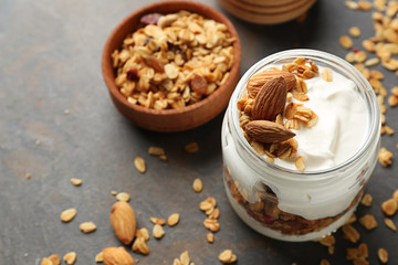 Glass jar of tasty yogurt with oatmeal and almonds on table