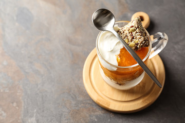 Glass cup of tasty yogurt with jam and candied nuts on table