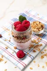 Glass jar of tasty yogurt with raspberry and oatmeal on table