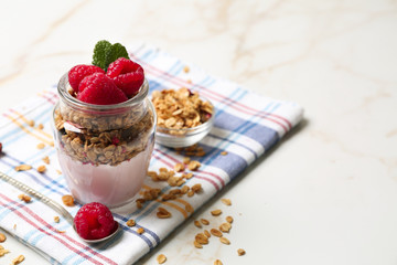 Glass jar of tasty yogurt with raspberry and oatmeal on table