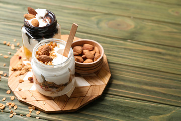 Glass jars of tasty yogurt with oatmeal and almonds on wooden table