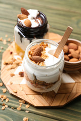 Glass jars of tasty yogurt with oatmeal and almonds on wooden table