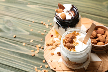Glass jars of tasty yogurt with oatmeal and almonds on wooden table