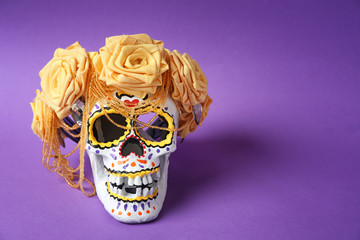 Painted human skull with flower wreath for Mexico's Day of the Dead on color background