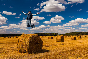 Naklejka na ściany i meble Young man jumping over haystack on the summer day.