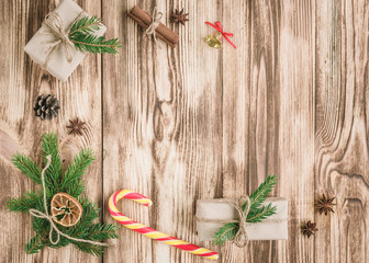 Christmas composition of fir branches with Christmas sticks, cones, cinnamon sticks, badian, balls, gift boxes on wooden table with copy space.